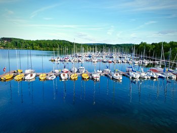 Kreissegelhafen Bostalsee Aus der Vogelperspektive ist der Kreissegelhafen mit unzähligen Segelbooten auf blauem Wasser mit grünen Hügeln im Hintergrund zu sehen.