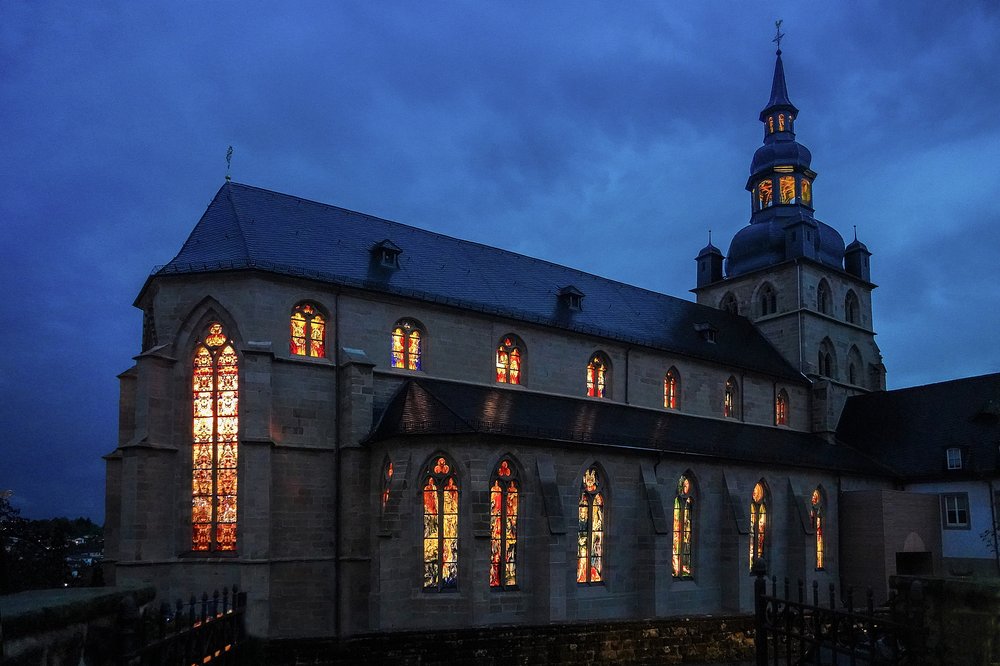 Individualangebot Abtei Gemeinde Tholey Im alleinigen Fokus des Bildes befindet sich die Benediktinierabtei Tholey bei Nacht. Aus den Fenstern der Abtei scheint helles Licht.