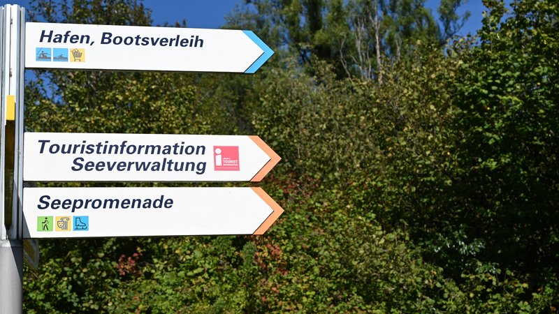 Drei Pfeilwegweiser mit den Aufschriften Hafen, Bootsverleih, Touristinformation, Seeverwaltung und Seepromenade