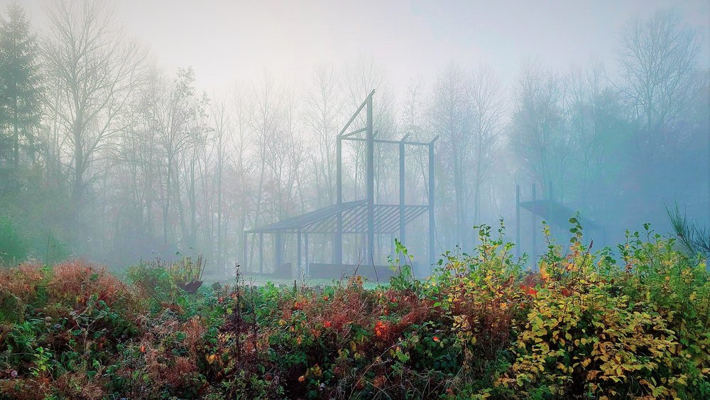 Mitten in einer mit Nebel bedeckten Landschaft ist ein römisches Baukunstwerk zu sehen.